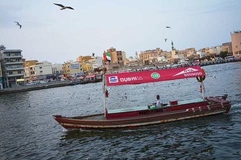 Sebuah perahu wisata tampak kosong saat melintasi Dubai Creek di dekat pasar Al Seef, Dubai, Uni Emirat Arab, Jumat, (13/03/2026).
