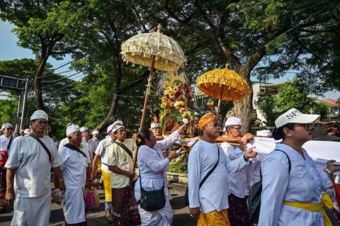Umat Hindu berjalan dengan membawa benda sakral menuju lokasi upacara Melasti di Pantai Kenjeran, Surabaya, Jawa Timur, Sabtu (14/3/2026).