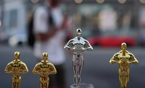 Seorang pria melewati replika patung Oscar pada hari Sabtu, 14 Maret 2026, di jalan dekat Dolby Theatre di Los Angeles, tempat persiapan terus berlangsung untuk upacara Academy Awards ke-98 p