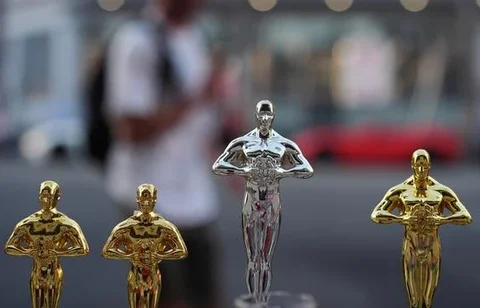 Seorang pria melewati replika patung Oscar pada hari Sabtu, 14 Maret 2026, di jalan dekat Dolby Theatre di Los Angeles, tempat persiapan terus berlangsung untuk upacara Academy Awards ke-98 p