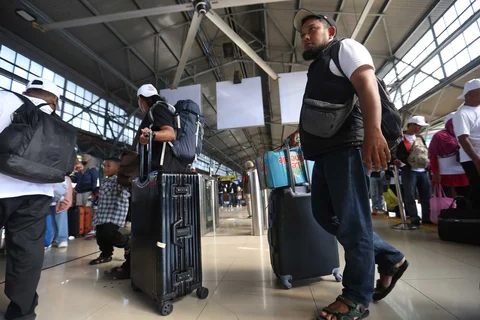 Pemudik tujuan Surabaya berjalan menuju gerbong kereta Jayakarta di Stasiun Senen, Jakarta, Senin (16/01/2026).
