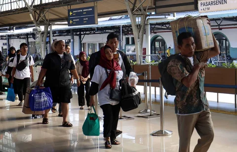 Pemudik tujuan Surabaya berjalan menuju gerbong kereta Jayakarta di Stasiun Senen, Jakarta, Senin (16/01/2026).