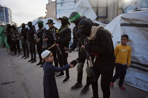 Seorang anak memberikan salam kepada para militan Hamas usai pelaksanaan salat Idul Fitri di Kota Gaza, Jumat, (20/03/2026).