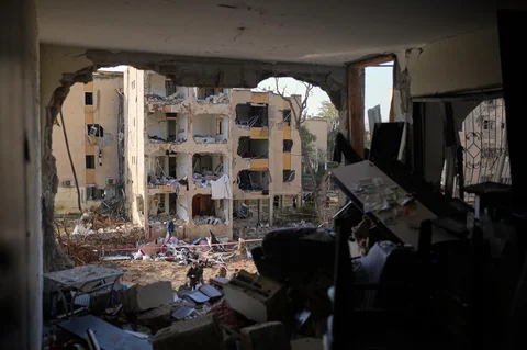 Warga melihat bangunan tempat tinggal yang rusak akibat serangan rudal Iran di Arad, Israel selatan, Minggu (22/03/2026).