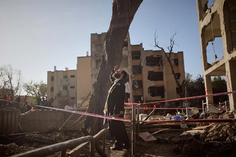 Warga melihat bangunan tempat tinggal yang rusak akibat serangan rudal Iran di Arad, Israel selatan, Minggu (22/03/2026).