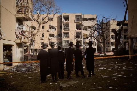 Warga melihat bangunan tempat tinggal yang rusak akibat serangan rudal Iran di Arad, Israel selatan, Minggu (22/03/2026).