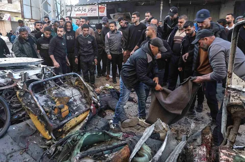 Warga mengevakuasi  jenazah dari jip polisi Palestina yang menjadi sasaran serangan udara Israel di kamp pengungsi Nuseirat di Jalur Gaza, Minggu (22/03/2026).