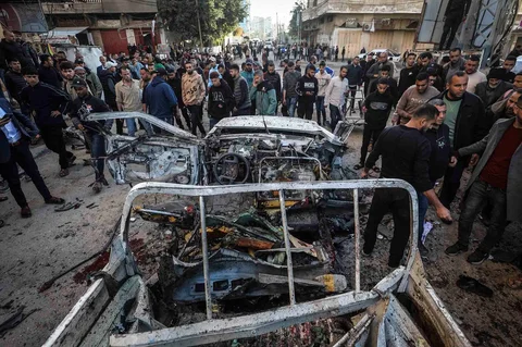 Warga berkerumun menyaksikan jip polisi Palestina yang menjadi sasaran serangan udara Israel di kamp pengungsi Nuseirat di Jalur Gaza, Minggu (22/03/2026).