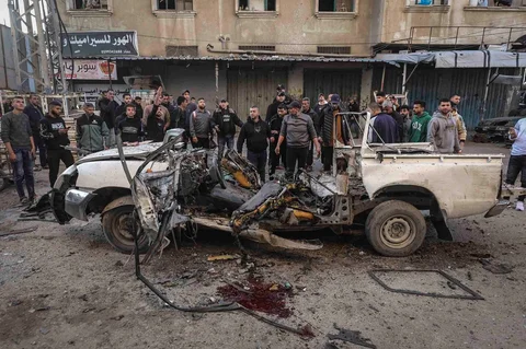Warga berkerumun menyaksikan jip polisi Palestina yang menjadi sasaran serangan udara Israel di kamp pengungsi Nuseirat di Jalur Gaza, Minggu (22/03/2026).