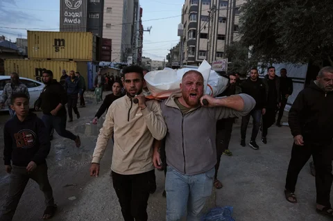 Para pelayat menggotong jenazah Ahmed Hamdan Tabasha, seorang polisi Palestina yang tewas dalam serangan militer Israel, selama pemakamannya di Rumah Sakit Al-Awda di Nuseirat, Jalur Gaza selatan, Minggu (22/03/2026).