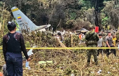 Warga dan tentara berdiri di dekat puing-puing pesawat Hercules Angkatan Udara yang jatuh saat lepas landas di Puerto Leguizamo, Kolombia, Kolombia. Senin (23/03/2026) waktu setempat.