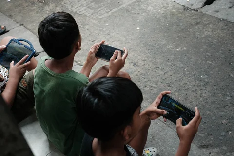 Anak-anak bermain game online satu sama lain di ponsel pintar dan tablet di sepanjang gang di Jakarta, (26/03/2026).