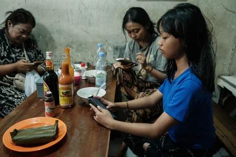 Seorang gadis berusia 11 tahun) menggunakan ponsel pintarnya setelah makan siang bersama keluarganya di sebuah restoran mie di Jakarta,  (26/03/2026).