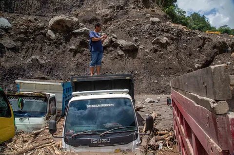 Warga berdiri di atas truk yang terkubur di pasir setelah banjir lahar dingn  dari Gunung Merapi di Sungai Senowo di Magelang, Jawa Tengah, Rabu (04/03/20026).