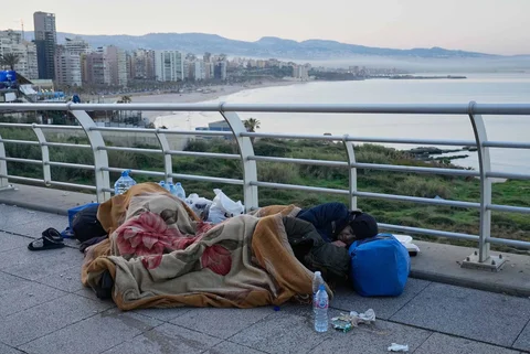 Para pengungsi yang melarikan diri dari serangan udara Israel di pinggiran selatan Beirut, Dahiyeh, duduk di tepi pantai Beirut, Lebanon, Jumat, (06/03/2026).