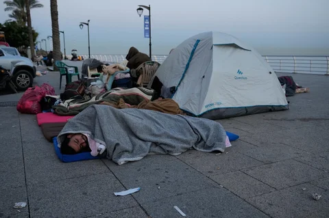 Para pengungsi yang melarikan diri dari serangan udara Israel di pinggiran selatan Beirut, Dahiyeh, duduk di tepi pantai Beirut, Lebanon, Jumat, (06/03/2026).