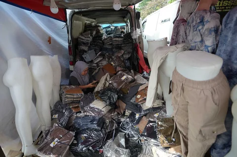 Warga berjalan melewati kendaraan pedagang yang menjual pakaian di Pasar Tasik, Cideng, Jakarta, Senin, (09/03/2026).