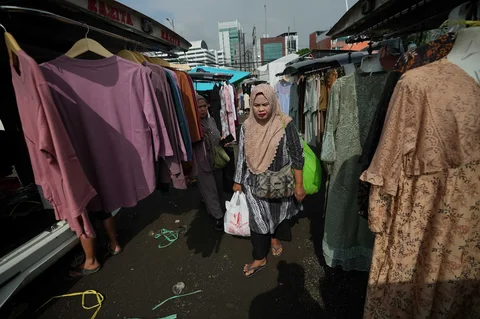 Warga berjalan melewati kendaraan pedagang yang menjual pakaian di Pasar Tasik, Cideng, Jakarta, Senin, (09/03/2026).