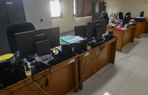 Staf bekerja di depan komputer dengan beberapa meja kursi yang kosong saat penerapan work from home (WFH) bagi aparatur sipil negara (ASN)  di kantor Kecamatan Limo, Depok, Jumat (10/04/2026).