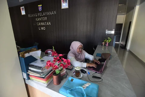 Staf bekerja di depan komputer dengan beberapa meja kursi yang kosong saat penerapan work from home (WFH) bagi aparatur sipil negara (ASN)  di kantor Kecamatan Limo, Depok, Jumat (10/04/2026).
