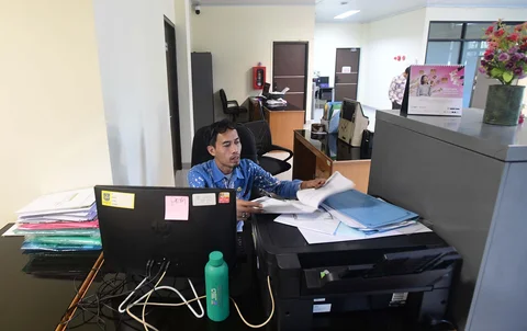 Staf bekerja di depan komputer dengan beberapa meja kursi yang kosong saat penerapan work from home (WFH) bagi aparatur sipil negara (ASN)  di kantor Kecamatan Limo, Depok, Jumat (10/04/2026).