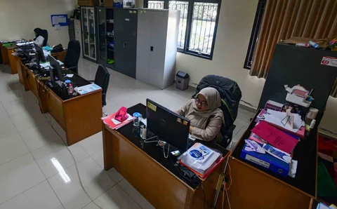Staf bekerja di depan komputer dengan beberapa meja kursi yang kosong saat penerapan work from home (WFH) bagi aparatur sipil negara (ASN)  di kantor Kecamatan Limo, Depok, Jumat (10/04/2026).