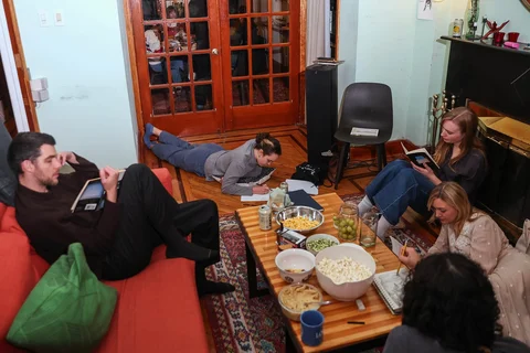 Para tamu membaca dalam keheningan selama pertemuan mingguan tanpa telepon di rumah penyelenggara Dan Fox di distrik Brooklyn, New York, AS,  (25/03/2026).