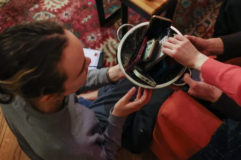 Para tamu mengambil kembali ponsel pintar mereka di akhir pertemuan mingguan tanpa ponsel di rumah penyelenggara Dan Fox di distrik Brooklyn, New York, AS, (25/03/2026).