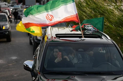 Seorang pengungsi melambaikan bendera Iran saat kembali bersama keluarganya ke desa mereka setelah gencatan senjata antara Hizbullah dan Israel, di Qasmiyeh dekat kota Tyre, Lebanon selatan, Jumat (17/04/2026).
