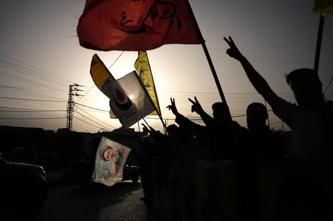 Warga mengibarkan bendera Hizbullah dan gambar mendiang pemimpin Hizbullah Hassan Nasrallah, di Zefta, Lebanon selatan, Jumat (17/04/2026), saat penduduk yang mengungsi kembali ke desa mereka setelah gencatan senjata antara Israel dan Hizbullah.