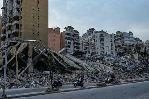 Warga yang mengendarai sepeda motor melewati reruntuhan bangunan yang hancur di Dahiyeh, pinggiran selatan Beirut, Lebanon, Jumat (17/04/2026), setelah gencatan senjata antara Israel dan Hizbullah.