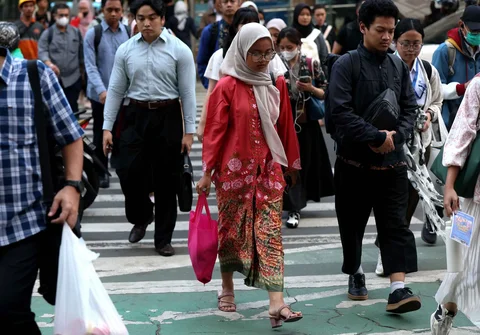 Pekerja wanita dengan mengenakan kebaya berjalan pulang kantor di kawasan Bunderan HI, Jakarta, Selasa (21/04/2026).