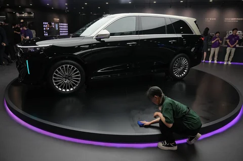 Seorang petugas kebersihan membersihkan area di dekat model V9X Hybrid terbaru dari Great Wall Motor (GWM)