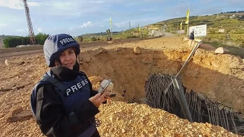 Jurnalis Lebanon Amal Khalil, yang bekerja untuk harian Al-Akhbar, melaporkan dari dekat jembatan yang hancur di Qasmiyeh, Lebanon, Minggu, 22 Maret 2026. (Dok. AP/Mohammed Zaatari)