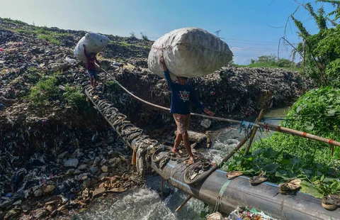 Warga mnyebrangi  Kali Pesanggrahan yang menyempit akbat longsoran timbunan sampah TPA Cipayung di kawasan Pasir Putih, Depok, Jawa Barat, Senin (27/04/2026).