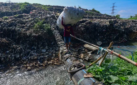 Warga mnyebrangi  Kali Pesanggrahan yang menyempit akbat longsoran timbunan sampah TPA Cipayung di kawasan Pasir Putih, Depok, Jawa Barat, Senin (27/04/2026).
