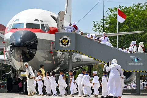 Para siswa dan guru taman kanak-kanak berjalan melewati pesawat Boeing 737 yang sudah tidak digunakan lagi saat mereka melakukan ritual tawaf mengelilingi replika Ka'bah di pusat ibadah haji di Banda Aceh, Senin (27/04/2026).