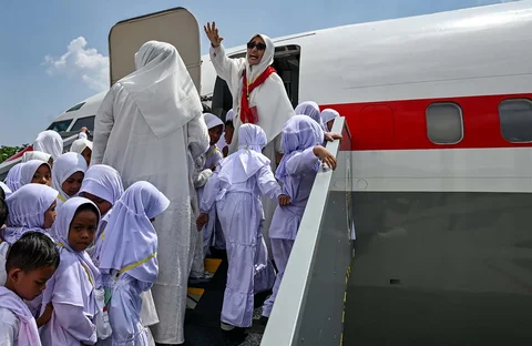 Para siswa dan guru taman kanak-kanak berjalan menaiki pesawat Boeing 737 yang sudah tidak digunakan lagi saat mereka melakukan manasik haji di pusat ibadah haji di Banda Aceh, Senin (27/04/2026).