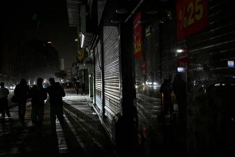 Orang-orang berjalan melewati toko-toko yang tutup lebih awal karena pemberlakuan jam malam yang diperintahkan pemerintah untuk mengurangi biaya energi di pusat kota Kairo,Kamis (02/04/2026) malam.