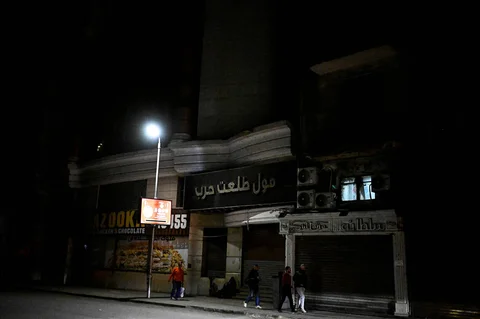 Orang-orang berjalan melewati toko-toko yang tutup lebih awal karena pemberlakuan jam malam yang diperintahkan pemerintah untuk mengurangi biaya energi di pusat kota Kairo,Kamis (02/04/2026) malam.