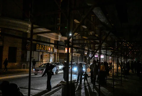 Orang-orang berjalan melewati toko-toko yang tutup lebih awal karena pemberlakuan jam malam yang diperintahkan pemerintah untuk mengurangi biaya energi di pusat kota Kairo,Kamis (02/04/2026) malam.
