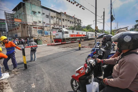 Pengendara bermotor menunggu kereta lewat pada palang pintu manual di perlintasan sebidang rel kereta api di Jalan Ampera, Bekasi, Jawa Barat, Kamis (30/04/2026).