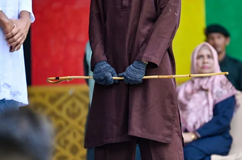 Algojo bersiap  mengeksekusi cambuk terpidana pelanggar peraturan daerah (qanun) tentang hukum syariat Islam di Panggung Taman Bustanussalatin, Banda Aceh, Aceh, Selasa (07/04/2026).