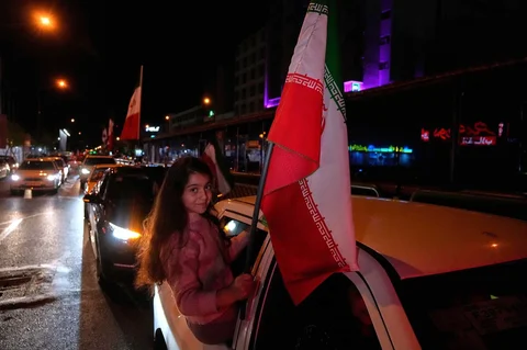 Seorang gadis memegang bendera Iran saat berkumpul setelah pengumuman gencatan senjata selama dua minggu dalam perang dengan Amerika Serikat dan Israel, di Jalan Enqelab-e-Eslami,  Teheran, Iran, Rabu, (08/04/2026).
