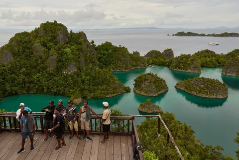Para wisatawan berdiri di sebuah titik pandang yang menghadap ke Kepulauan Waigeo Barat di Raja Ampat, Indonesia, Kamis (05/03/2026).