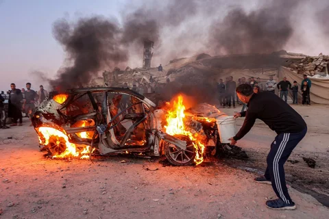 Seorang pria menggunakan ember saat mencoba memadamkan api yang membakar kendaraan jurnalis Palestina Mohammed Washeha setelah serangan di selatan Kota Gaza, Palestina, Rabu (08/04/2026).