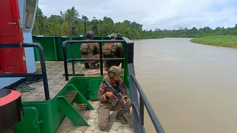 Personel Satgas Operasi Damai Cartenz 2026 bersama Polres Yahukimo mengawal enam kapal pengangkut bahan bakar minyak dan bahan makanan saat tiba di  Distrik Kolof Brazai, Kabupaten Yahukimo, Papua Pegunungan, Sabtu (9/5/2026).
