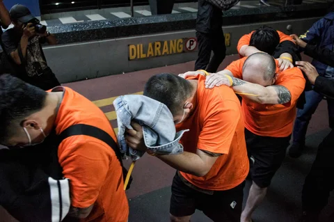 Personel kepolisian menggiring sejumlah tersangka kasus perjudian daring di Perkantoran Hayam Wuruk Plaza Tower, Jakarta, Minggu (10/5/2026).