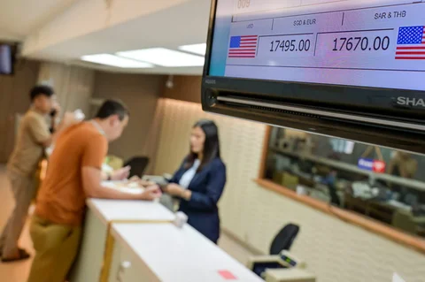 Sebuah monitor menampilkan kurs jual dan beli Rupiah terhadap Dolar AS, saat seorang penukar uang melayani pelanggan  di Jakarta, Selasa (12/05/2026).