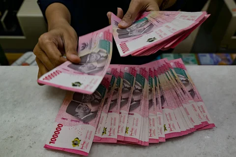 Seorang penukar uang menghitung uang kertas Rupiah di kantor penukaran uang di Jakarta,  Selasa (12/05/2026).